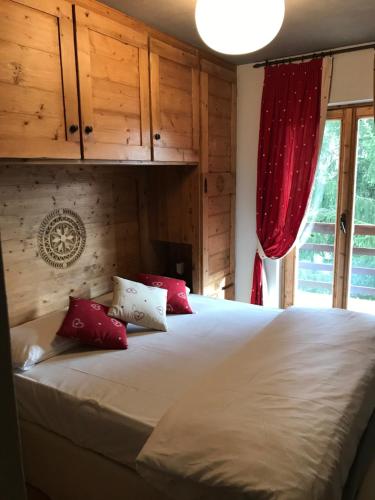 ein Schlafzimmer mit einem großen weißen Bett mit roten Kissen in der Unterkunft APPARTAMENTO SONNE in Ponte di Legno