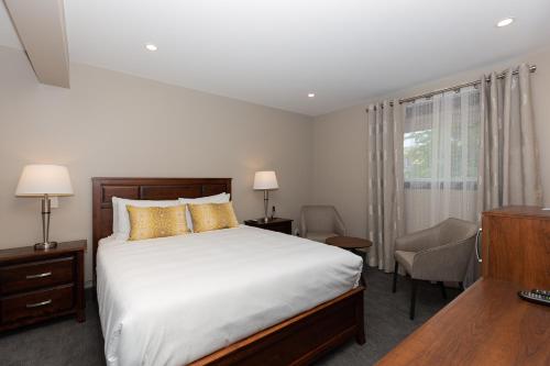 a bedroom with a bed and a desk and a window at Motel au Vieux Piloteux in Rivière-du-Loup