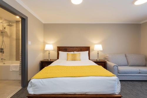 a bedroom with a bed and a chair and a tub at Motel au Vieux Piloteux in Rivière-du-Loup