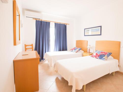 a hotel room with two beds and a table at Apartamentos Quinta da Praia in Alvor