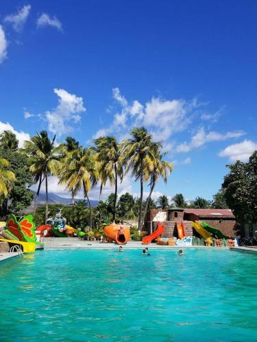 a large swimming pool with slides and palm trees at Hotel Pasabien in Huité