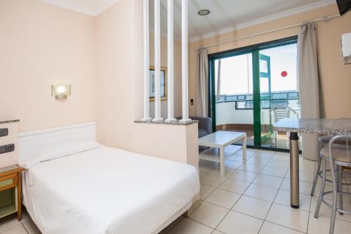 a hotel room with a bed and a table at Apartamentos Olympia in Playa del Ingles