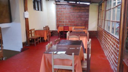Habitación con mesas, sillas y pared de ladrillo. en Mamá Alejita, en Ollantaytambo