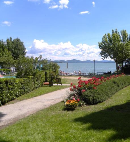 a path in a park with flowers in the grass at Hotel Kursaal in Passignano sul Trasimeno