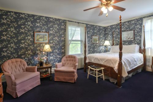 ein Schlafzimmer mit einem Bett und zwei Stühlen in der Unterkunft 1898 Waverly Inn in Hendersonville