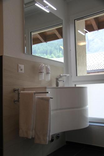 a bathroom with a sink and a mirror and towels at Therme 51° Hotel Physio & Spa in Leukerbad