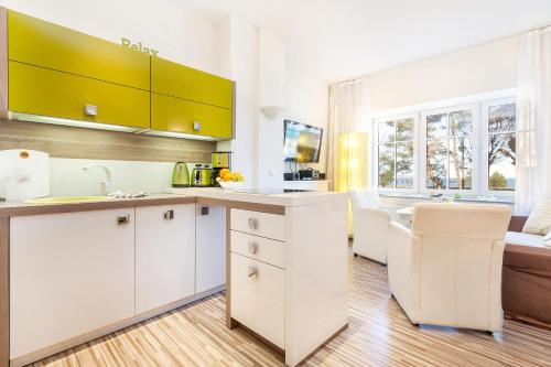 a kitchen with white cabinets and a table and a couch at Direkt am Strand mit Meerblick und Sauna - FeWo Strandidyll in Binz