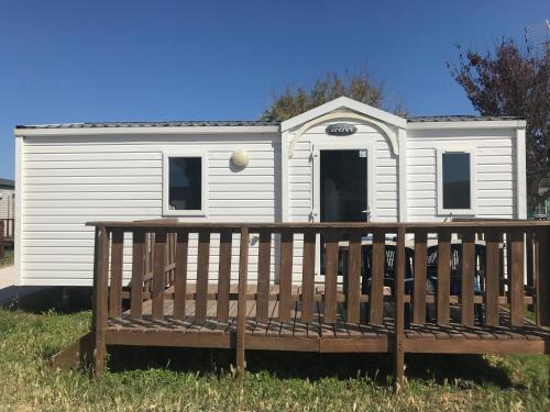 a small white house with a wooden deck at Camping Horizon Bar in Frontignan