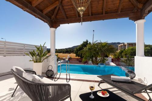 a patio with a table and chairs and a swimming pool at Elena House in Gennadi