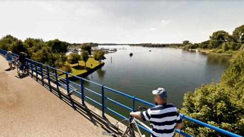 a man riding a bike on a bridge over a river at Loft 8 Linden in Groot-Linden