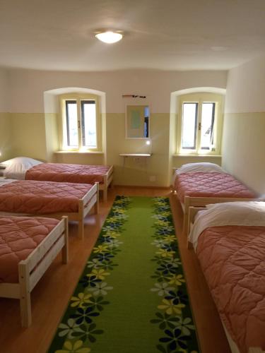 Habitación con 4 camas y alfombra verde. en Gostilna Tratnik, en Zoll