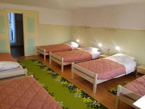 a room with three beds and a green rug at Gostilna Tratnik in Zoll