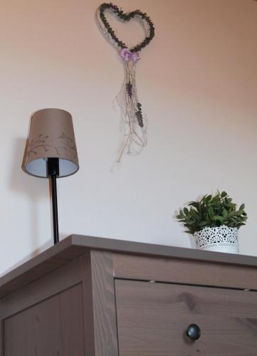 a heart decoration on the wall above a dresser with a lamp at Srub Losiny in Velké Losiny