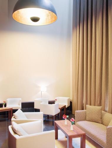 a living room with white furniture and a large light fixture at Mövenpick Hotel Hamburg City in Hamburg