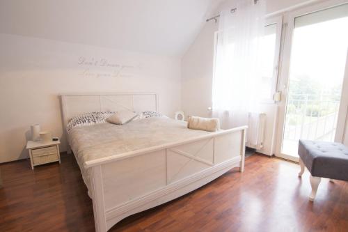 a white bed in a room with a large window at Dolce Casa in Belgrade