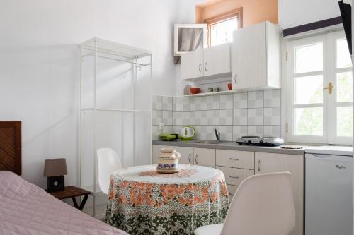 una cocina blanca con mesa y sillas en una habitación en Cozy & peaceful apartment in Chalki en Khalkíon