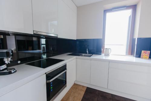 a white kitchen with black appliances and a window at Sea Towers Gdynia in Gdynia