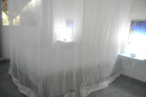 a white curtain in a room with a window at an eol caraibes in Trois-Rivières