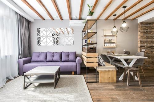 バコヴェルにあるApartment Bukovel for 6 adults Апартаменти Буковель для 6 дорослихの紫色のソファとテーブル付きのリビングルーム