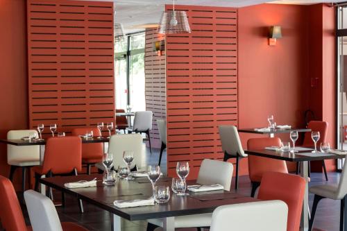 un restaurant avec des tables, des chaises et des murs rouges dans l'établissement Le Cottage de Clairefontaine, à Chonas-lʼAmballan
