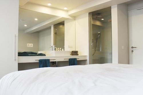 een slaapkamer met een groot wit bed en een badkamer bij Remacle3 in Stavelot
