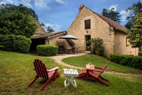 two chairs and a table in front of a house at Le Petit Manoir de Vitrac in Vitrac