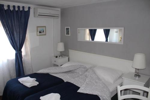 a white bedroom with a bed and a mirror at Karmelita's place -studio in Šibenik