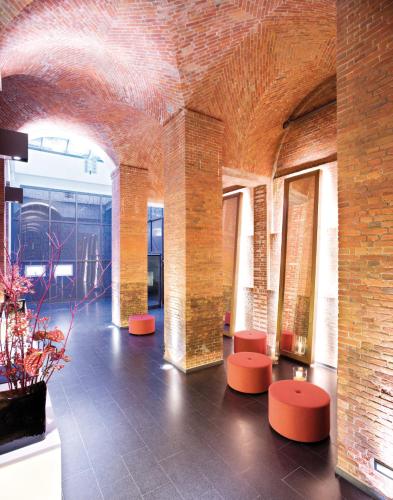 a room with red stools and a brick wall at Mövenpick Hotel Hamburg City in Hamburg