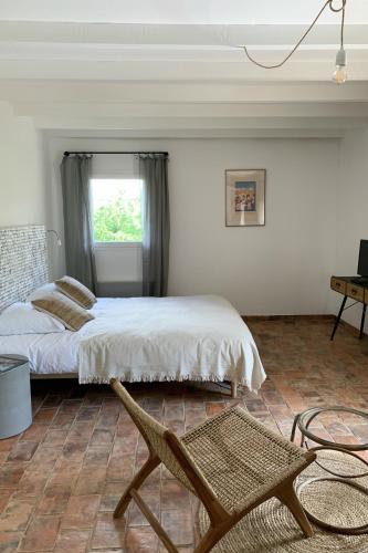 une chambre avec un lit, une chaise et une fenêtre dans l'établissement Domaine de Carraire, à Aix-en-Provence