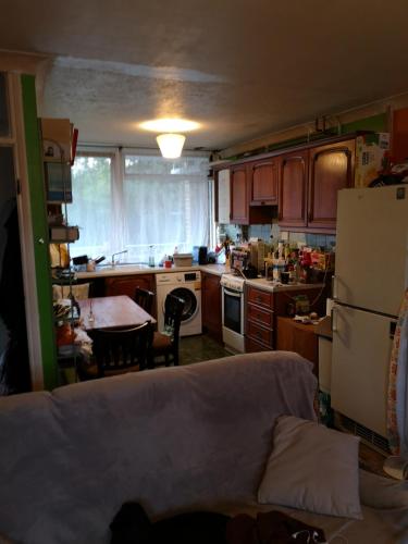 a kitchen with a couch and a table and a refrigerator at Quiet room in Eltham in London