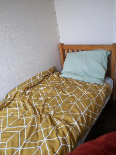 a bed with a yellow and white comforter and a pillow at Quiet room in Eltham in London