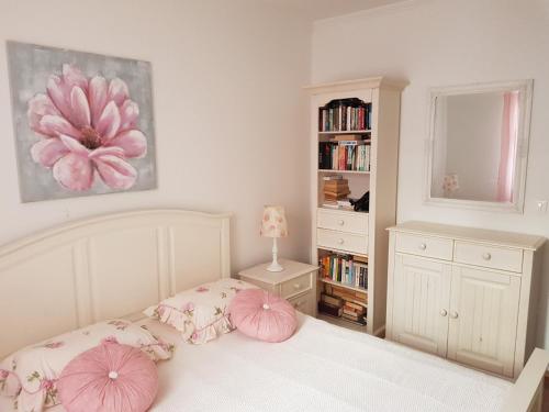 ein Schlafzimmer mit einem Bett mit rosa Kissen und einem Bücherregal in der Unterkunft Cozy apartment in Rovinj in Rovinj