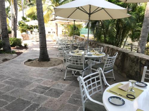 a row of tables and chairs with an umbrella at Grand Isla Navidad Golf & Spa Resort with Marina in Barra de Navidad