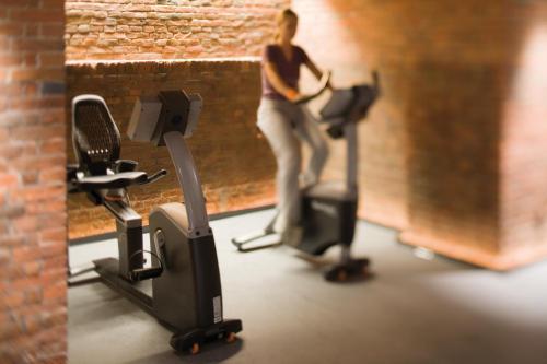 a woman standing on an exercise bike in a gym at Mövenpick Hotel Hamburg in Hamburg