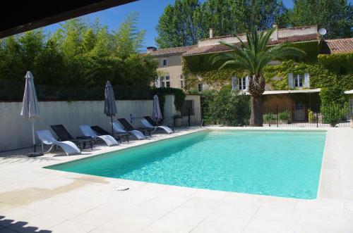 a swimming pool with chairs and umbrellas next to a house at Le Domaine de Patris in Pernes-les-Fontaines