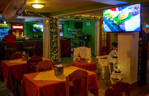 a restaurant with tables and a tv in a room at Hotel Andrea in Neily