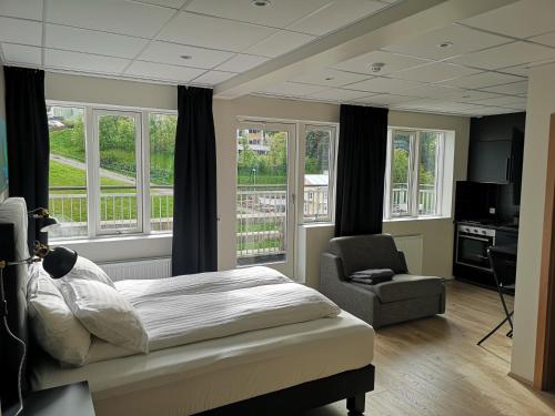a bedroom with a bed and a chair and windows at Centrum Hotel in Akureyri