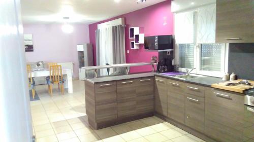 une cuisine avec des murs roses et des placards en bois dans l'établissement la maison du bonheur, à Roquetoire