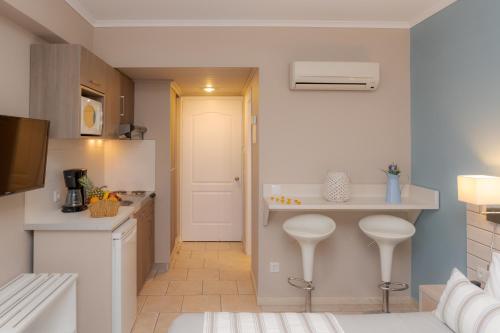 a kitchen with a counter and two stools in it at Theoxenia Chios Apartments in Paralia Agias Foteinis