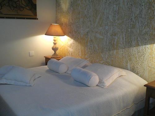 a white bed with white pillows and a lamp at Pousada da Mantiqueira in Visconde De Maua