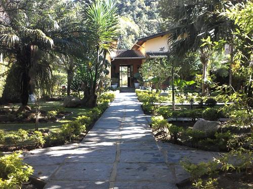 a walkway in front of a house with palm trees at Pousada da Mantiqueira in Visconde De Maua