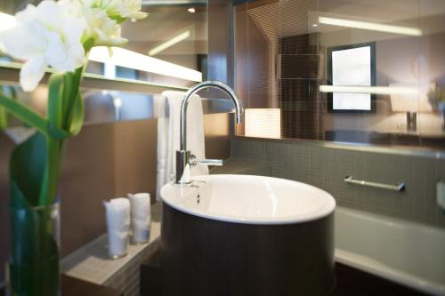 a bathroom with a sink and a vase of flowers at Mövenpick Hotel Hamburg City in Hamburg
