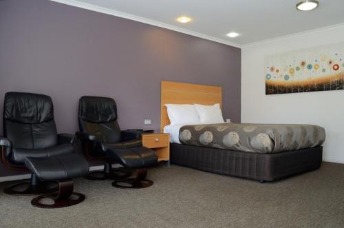 a hotel room with a bed and two chairs at Sportsmans Motor Inn in Barooga
