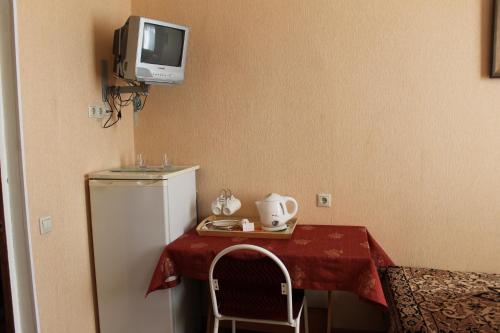 ドモジェドヴォにあるTatyana Hotelのテーブル、冷蔵庫、テレビが備わる客室です。