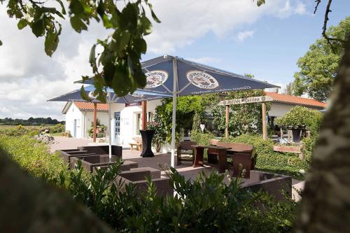 a pavilion with a table and a blue umbrella at Ostseehotel Hunhoi in Niesgrau