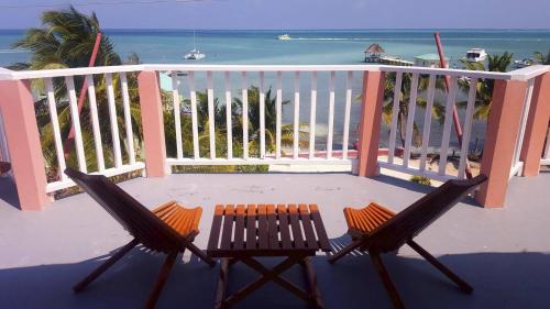 two chairs and a table on a balcony with the ocean at Caye Caulker Condos in Caye Caulker