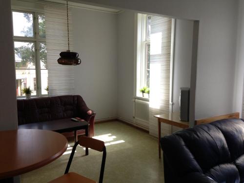 a living room with a couch and a table and two windows at Ronneby Brunnspark Vandrarhem och B&B in Ronneby