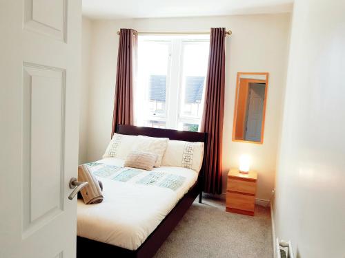 Three Bed Holiday Home in Glasgow في غلاسكو: غرفة نوم صغيرة مع سرير مع نافذة