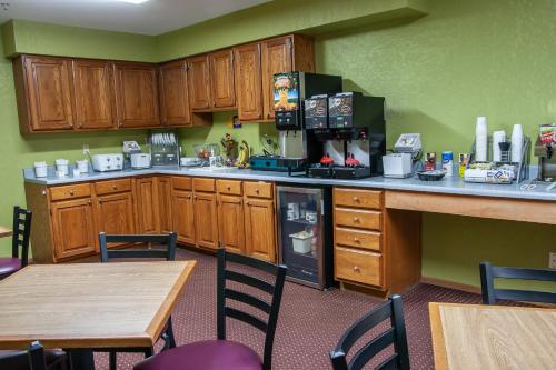 a kitchen with wooden cabinets and a table and chairs at Super 8 by Wyndham Arkansas City KS in Arkansas City
