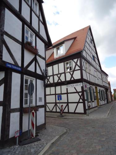 a black and white building next to a street at Pension Am Buhnenkopf in Tangermünde